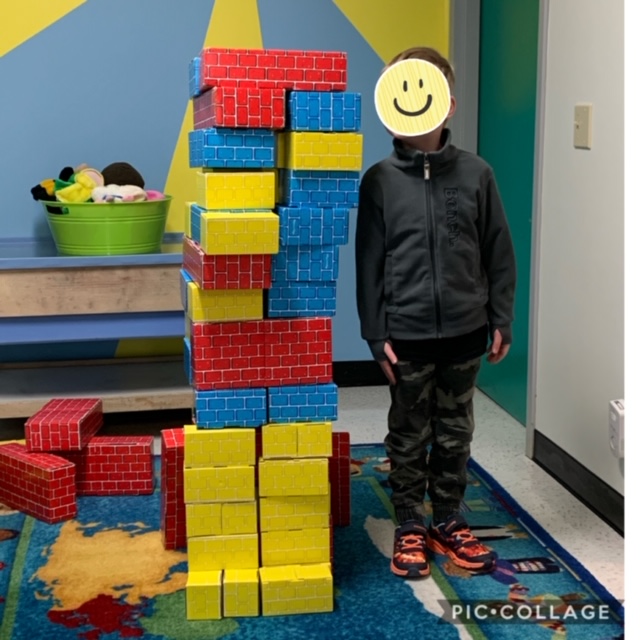 4 year-old measuring how tall he his after building blocks in block corner at Lessard Playschool preschool program