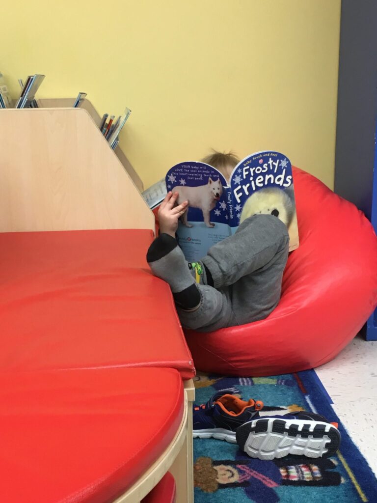 child reading book in book corner at Lessard Playschool